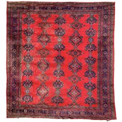 Antique Turkish crimson ground carpet, the field decorated with five alternating rows of pole medallions with lozenges and stylised plant motifs, the multi-band indigo border with repeating flower heads and branches
