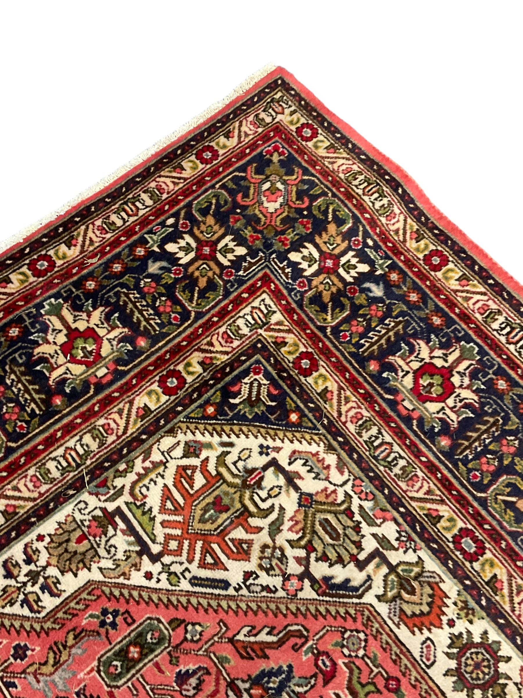 North West Persian pink ground Tabriz carpet, central indigo ground medallion surrounded by stylised plant motifs and trailing foliage, the main border with overall floral design within guard stripes 