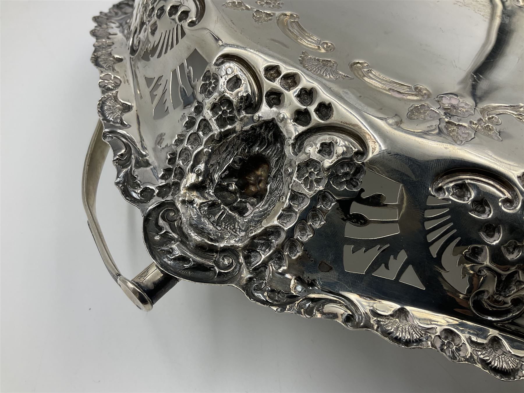 Edwardian silver swing handled basket, of navette form, with four repousse lion masks to each corner and with pierced and embossed floral, scroll and shell decoration to sides, base and handle, hallmarked Charles Horner, Birmingham 1906, height including handle H20cm