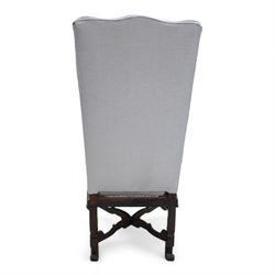 Carolean design walnut and oak wingback open armchair, the high wingback upholstered in light blue herringbone fabric, acanthus leaf carved arms with scrolled terminals and on scrolled supports, cane work seat with squab cushion and scatter cushion, the lower rail carved and pierced with putti holding crown surrounded by curled acanthus leaves, leaf carved S-scroll supports united by Scrolled X-framed stretchers 