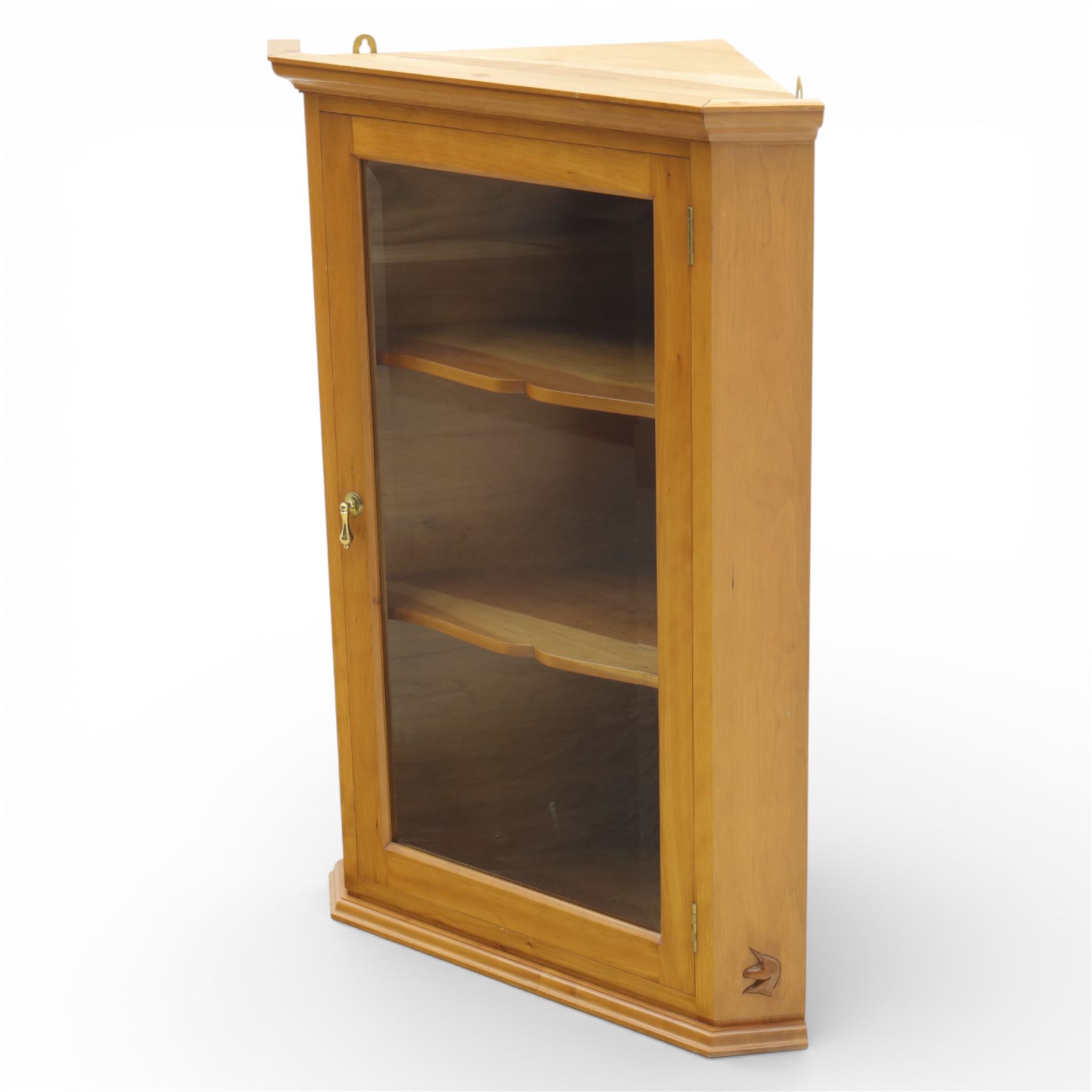 Unicornman - glazed oak corner cabinet, the triangular top with moulded cornice above a bevelled glass door, enclosing two fixed shelves, the canted front corner carved with Unicorn motif, by Geoff Gell of Coxwold