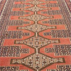 North West Persian Senneh hand-knotted runner, decorated with a continuous series of stepped and hooked geometric medallions against a madder red ground, enclosing herati style and small geometric floral motifs, framed by a principal border and flanked by multiple narrow guard stripes, with cotton fringe ends 