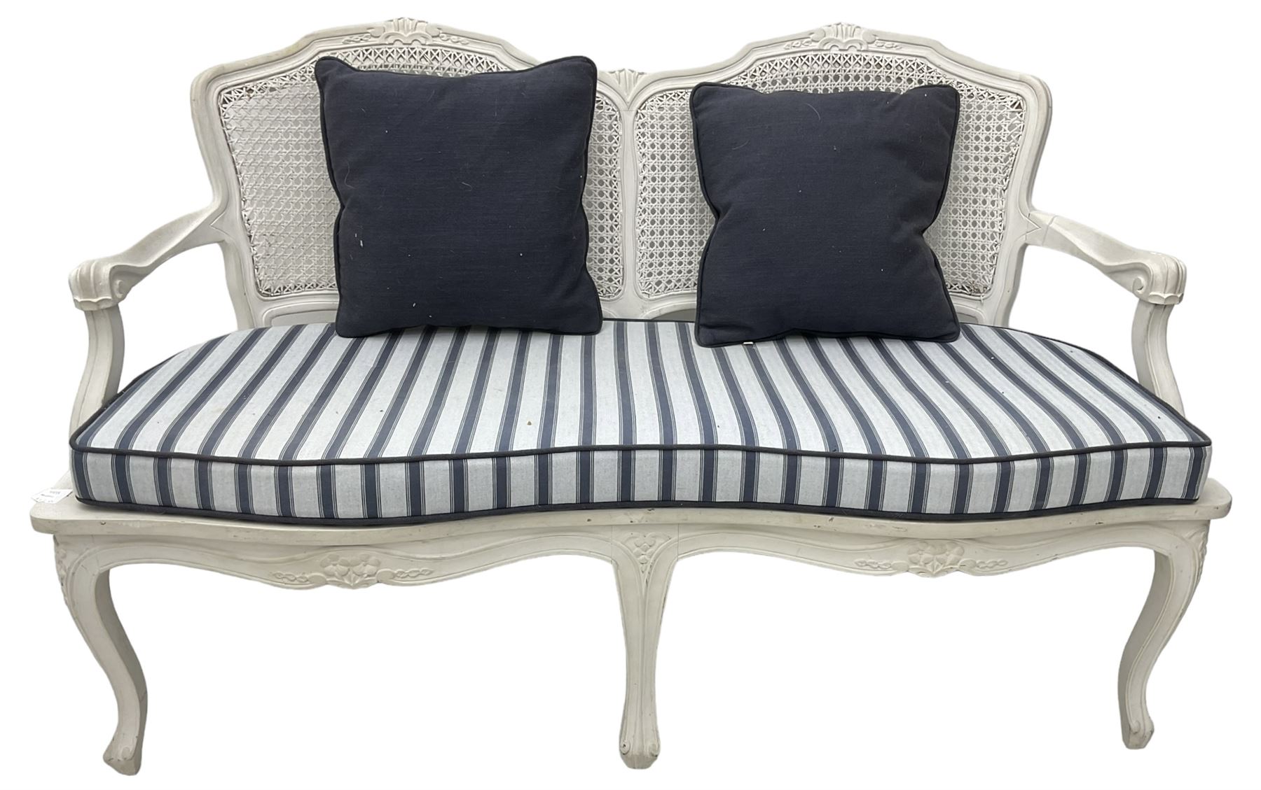 French design white painted two seat serpentine settee, floral carved cresting rail over cane back, loose striped upholstered seat cushion, on cabriole supports