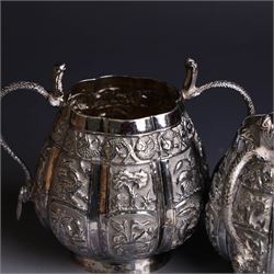 Three piece Indian silver tea service, comprising teapot, twin handled open sucrier and cream jug, each with embossed animal decoration with fish border, serpent handles and elephant finial, teapot H17cm