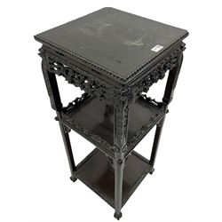 Early 20th century Oriental hardwood plant stand, the square top with bead moulded edge, two undertiers joined by supports carved with dragon masks and foliage, the frieze and raised panels carved and pierced with flower heads and foliate