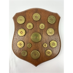 Long oak panel inset with 128 brass 12-bore cartridge caps, various ages and makers, L177cm; another shield shaped mahogany panel inset with different bores of brass cartridge caps including 4,8,10,12,14,16,20,24,28,32,360 & 410 H17.5cm (2)