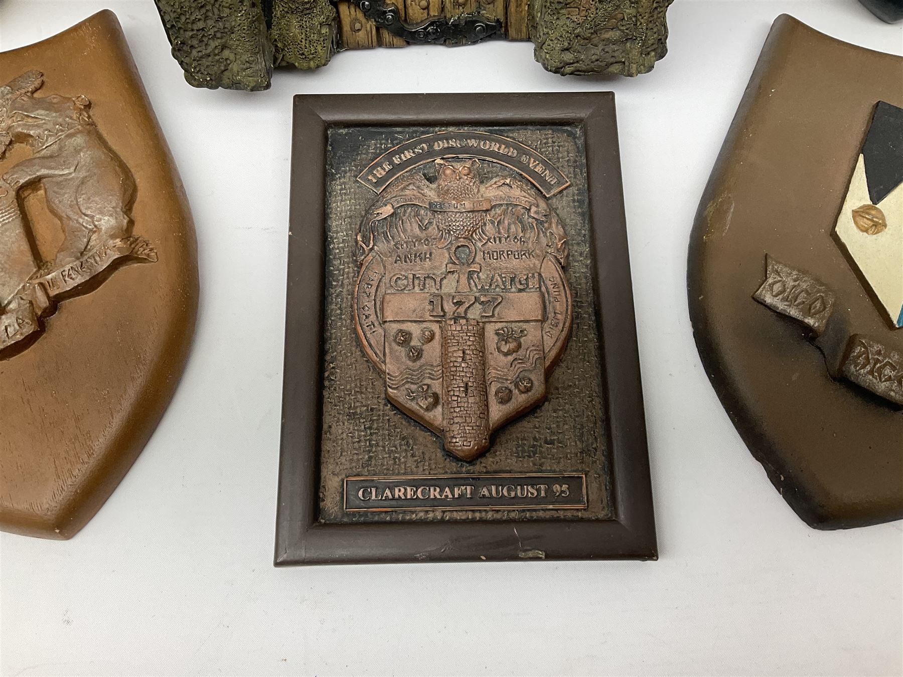 Terry Pratchett Discworld plaques, designed by Clarecraft, comprising 'the First Discworld Event Clarecraft August 95', the collectors guild joining shield, the fools guild DW99C, the seamstresses guild DW98C, the musicians guild DW00C together with 'Door of the mended drum' wall hanging DW17. 