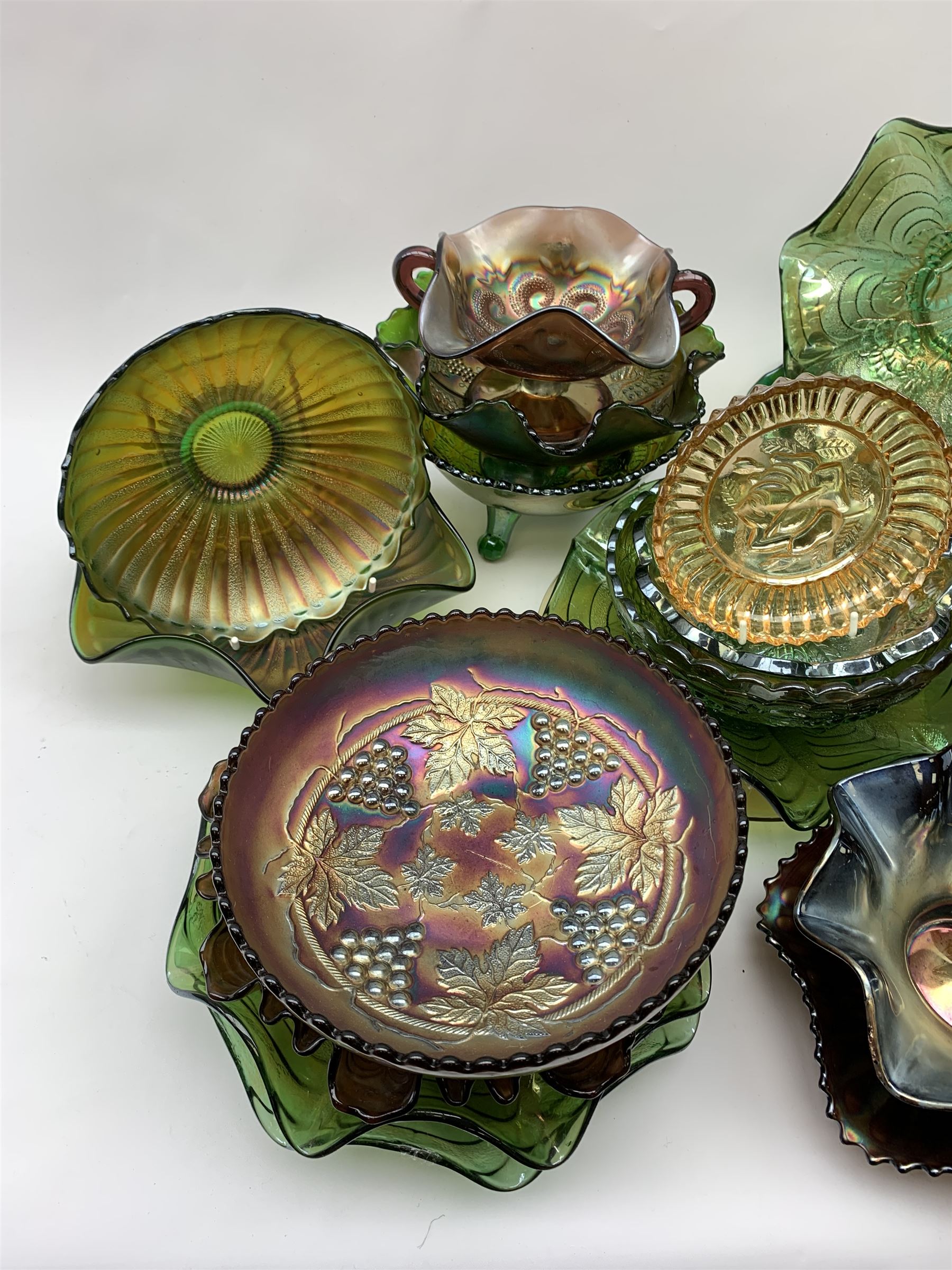 A collection of Carnival glass, to include marigold, green, and amethyst, bowls, dishes, and comports, various patterns including fruiting vines, peacocks, and an example decorated with a Horseshoe and detailed Good Luck. 

