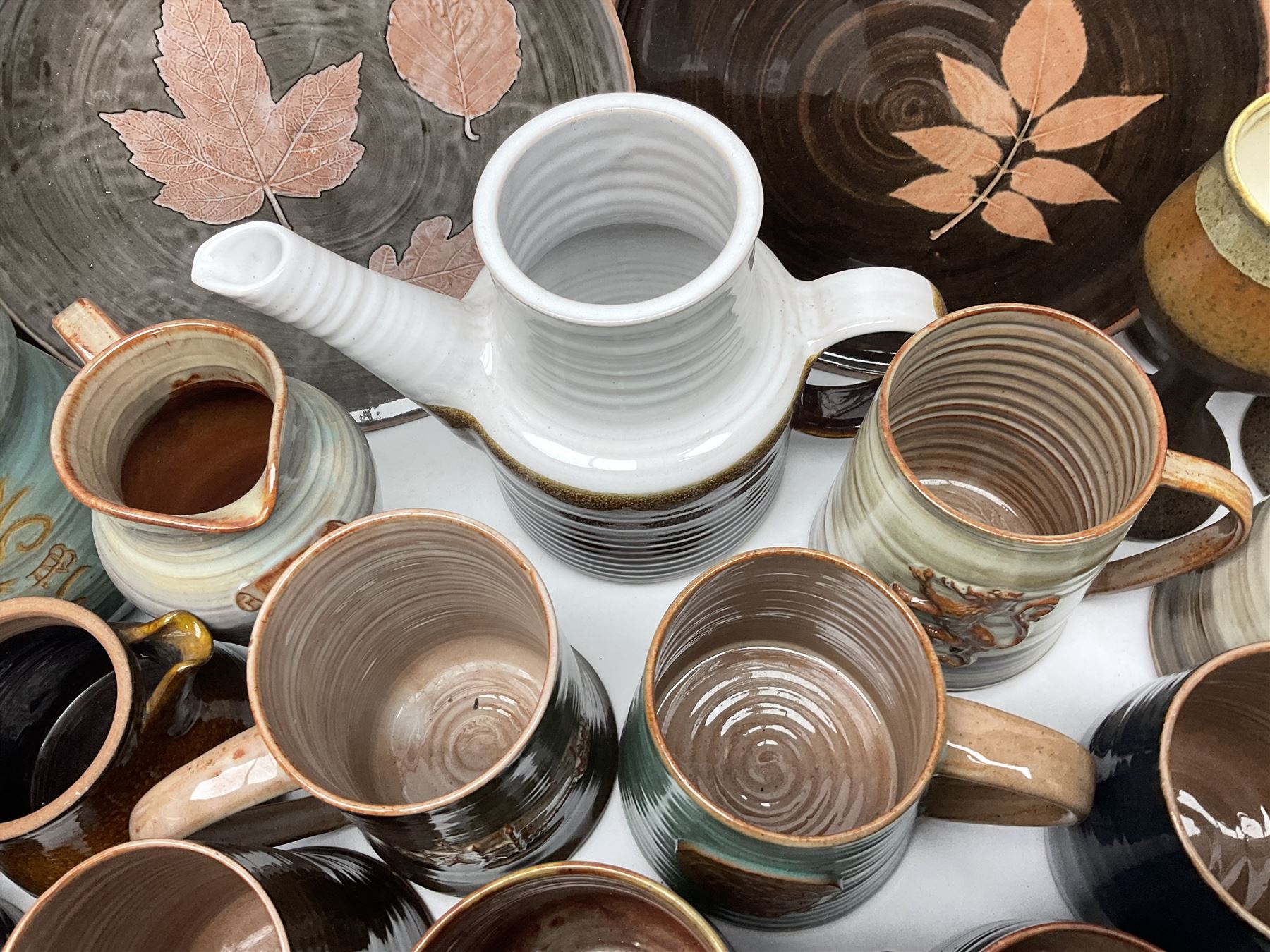 Wold studio pottery tankards, in various colours and relief decoration together with other studio items including vases, jugs and pots 