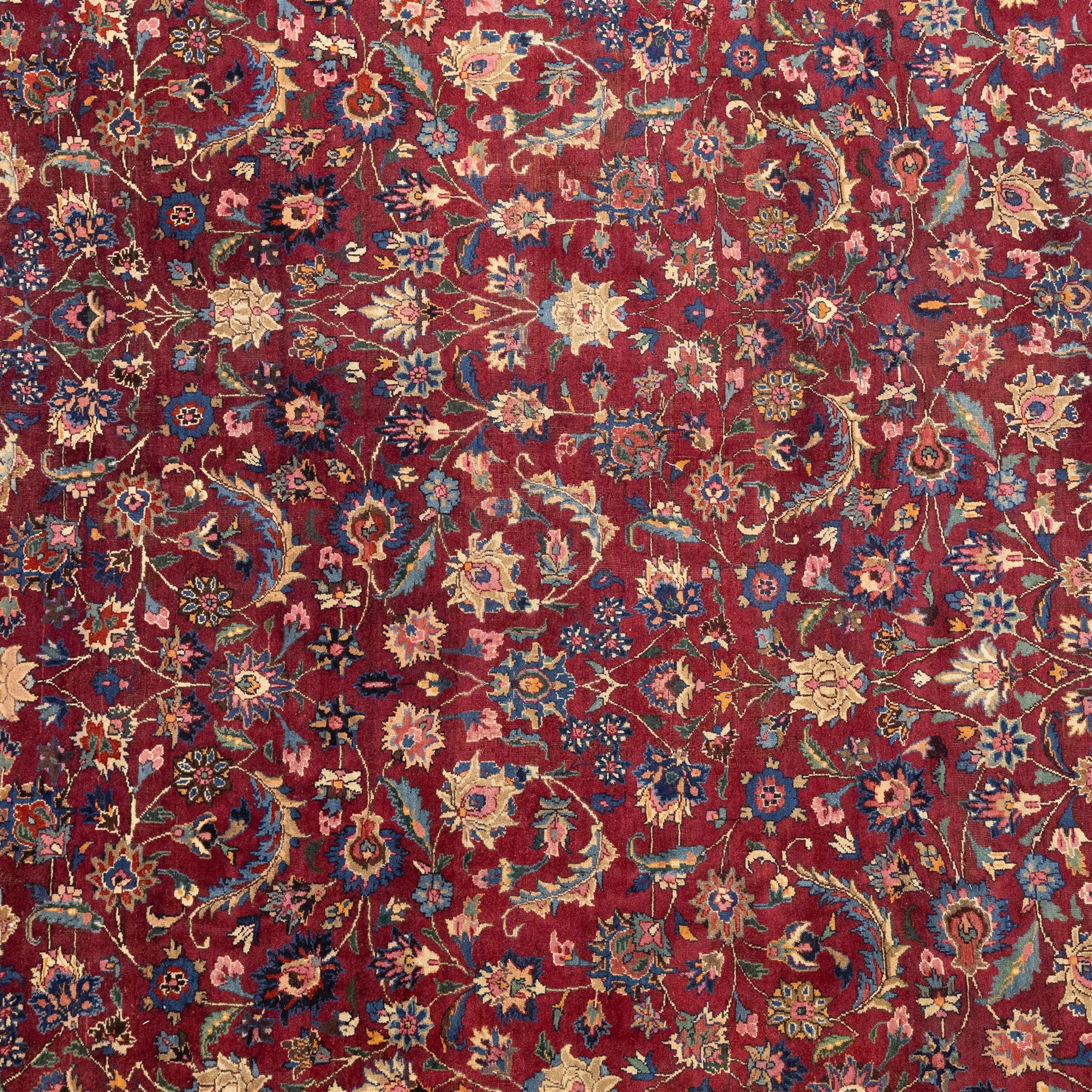 North East Persian Meshed hand-knotted carpet, rich red all-over field of finely decorated with dense scrolling floral sprays and palmettes and flowering vines, enclosed by a broad border in soft pastel tones, flanked by multiple guard borders, with cotton fringe ends  