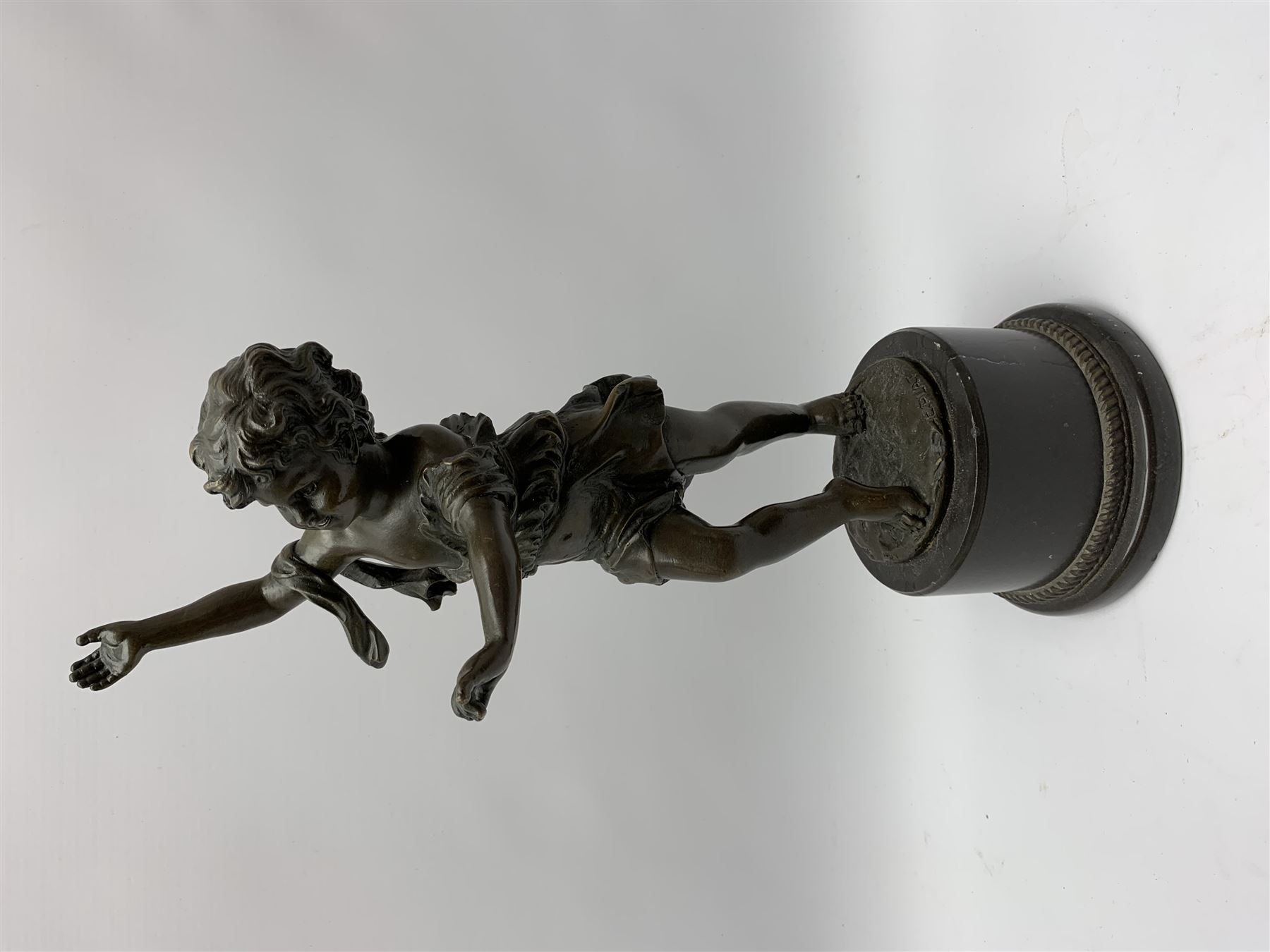 After E Plat, bronze modelled as a dancing child, signed E. Plat, upon cylindrical black marble base, H40cm