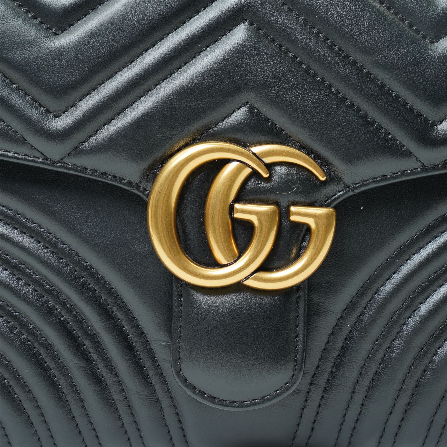 Gucci GG Marmont black matelassé leather top handle bag, made in Italy, with chevron quilted leather and heart motif to the reverse, antique gold-tone Double G front hardware, leather top handle and detachable chain shoulder strap with leather shoulder guard, front flap closure, suede-effect interior with zip pocket and leather logo tab stamped Gucci made in Italy, together with original Gucci dust bag and carrier, W27cm D11cm H20cm