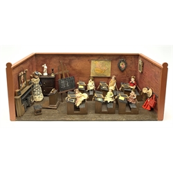 Late Victorian wooden school room setting with bisque head teacher and six German all bisque pupils each seated at a combined desk and chair with slate board, in a classroom furnished with chest of drawers, fire-surround, lectern, wall map, pictures, miniature books, school bell, chalk board on easel, wall clock etc, L70cm H28cm D28cm