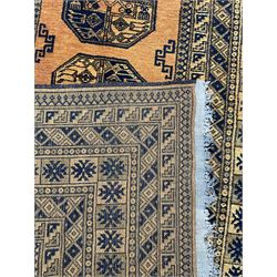 Persian Bokhara gold ground rug, three Gul motifs enclosed by multiple patterned border bands