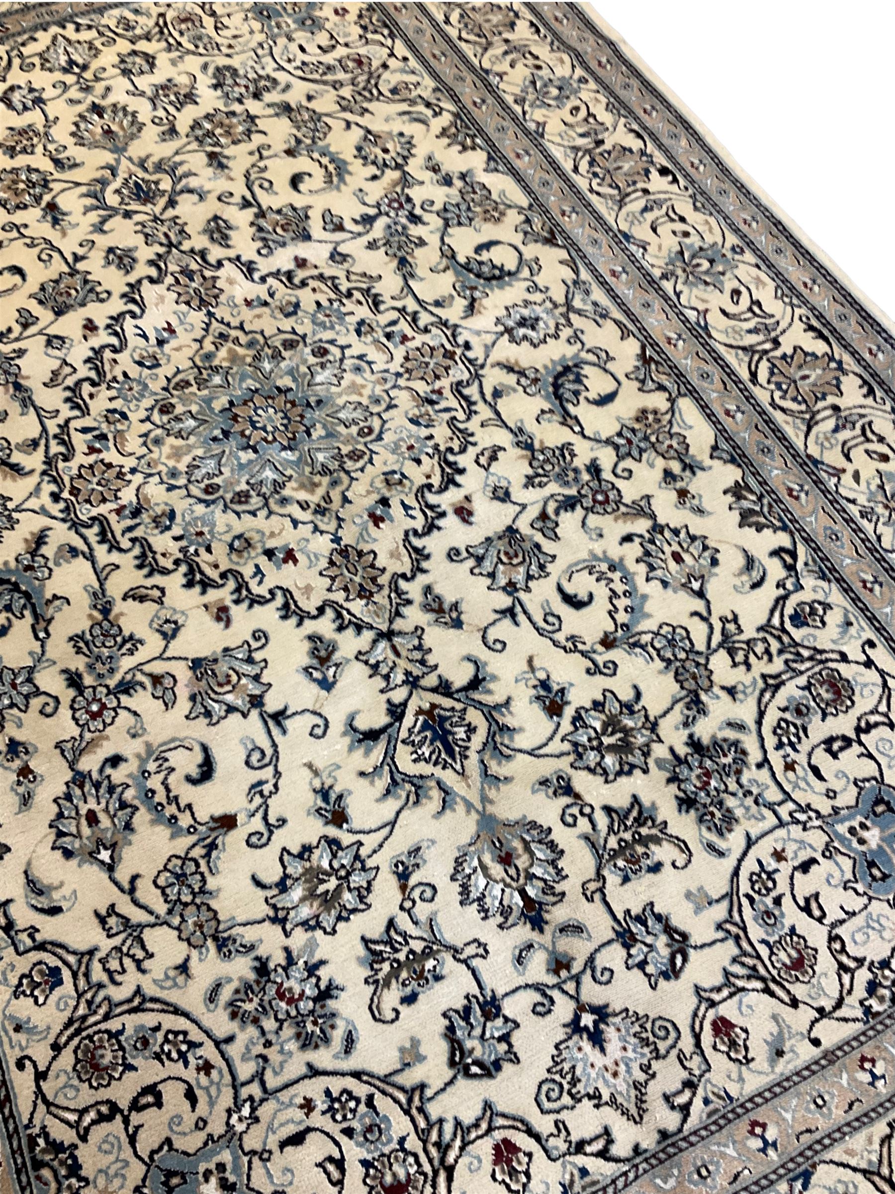 Central Persian Nain rug, wool with silk inlay, ivory ground decorated with scrolling and interlaced branch with stylised plant motifs, central floral medallion, triple band border with repeating design