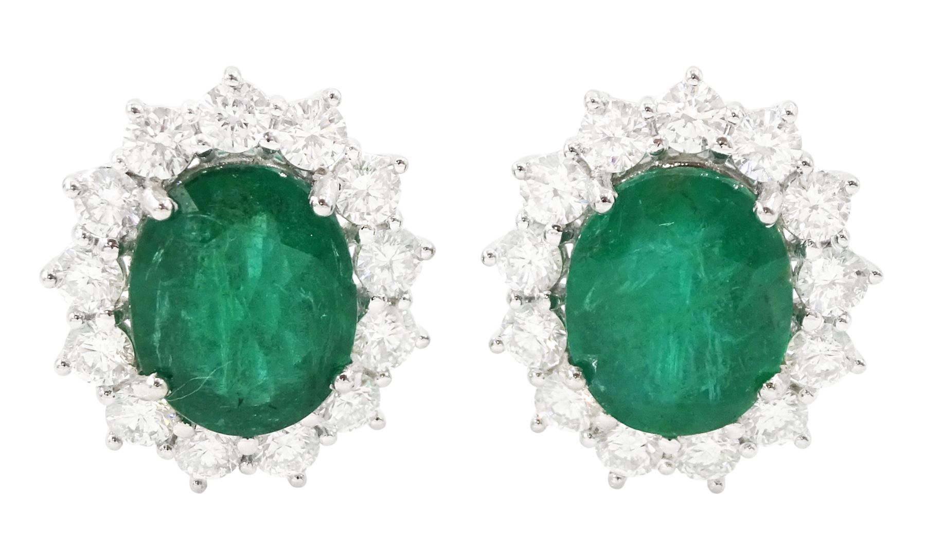 Pair of 18ct white gold emerald and diamond cluster earrings, each stud set with a single oval cut emerald, surrounded by thirteen round brilliant cut diamonds, stamped, total emerald weight approx 7.20 carat, total diamond weight approx 2.30 carat