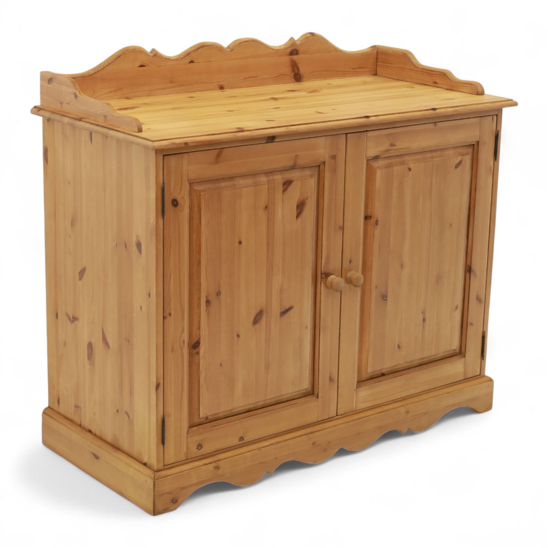 Contemporary pine cupboard, with raised shaped gallery over plain top, panelled double doors below with turned knob handles, shaped apron and plinth base