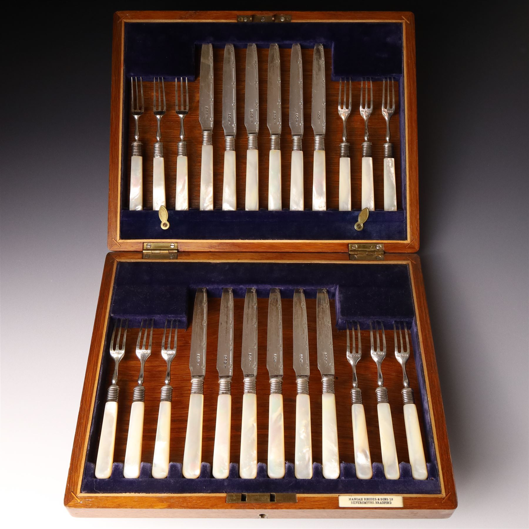 Set of twelve silver bladed fruit knives and forks with mother of pearl handles, the blades with engraved decoration, in oak case Sheffield 1920 Maker Allen & Darwin