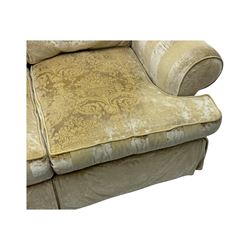 Contemporary two-seat sofa, upholstered in damask fabric with a pale gold floral pattern, rolled arms with covers, loose back and seat cushions, on matching skirted base with concealed castors