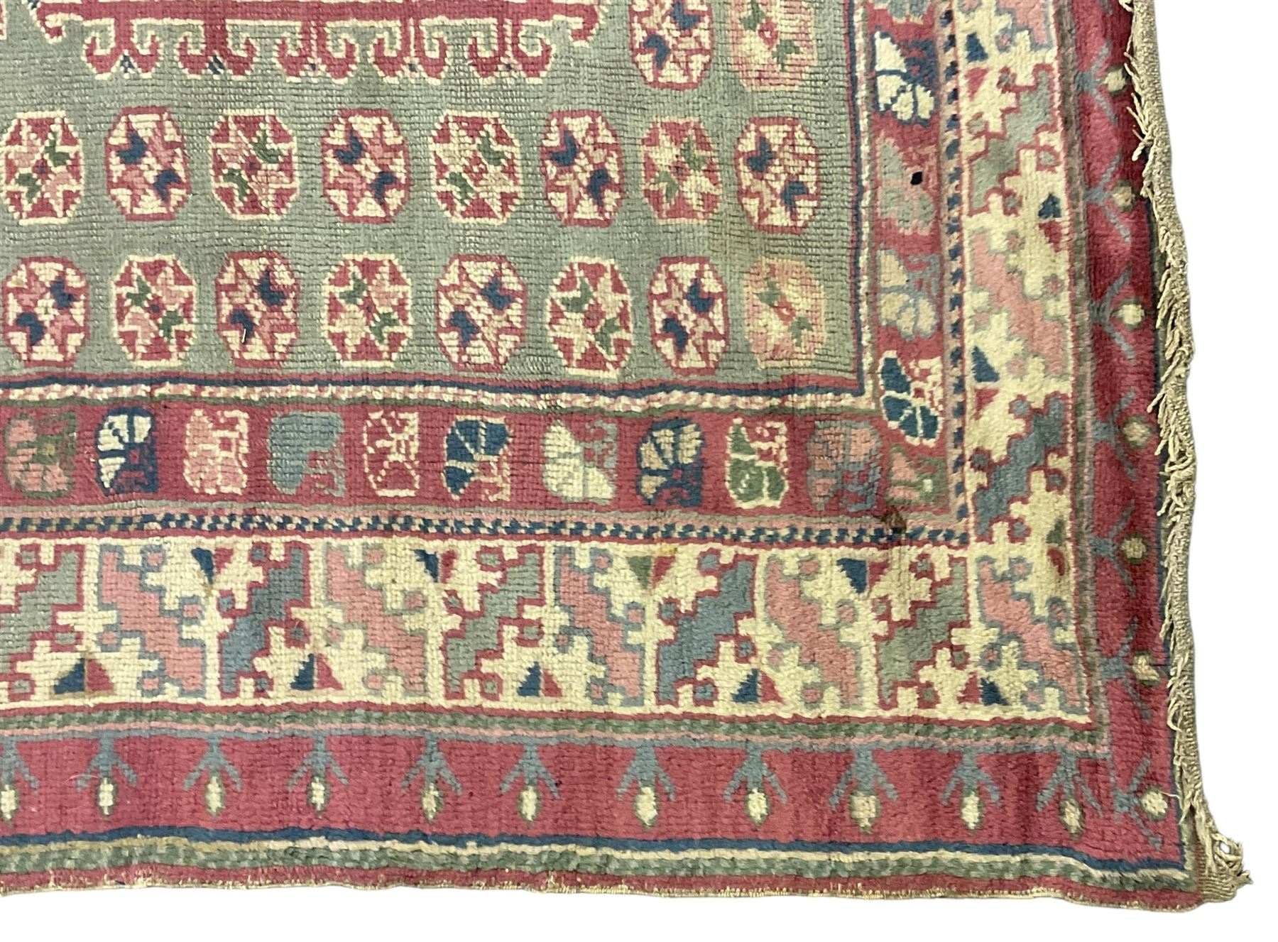 Turkish deep pink and green ground carpet, the square field with hooked borders surrounded by geometric motifs, multi-band border with overall geometric designs 