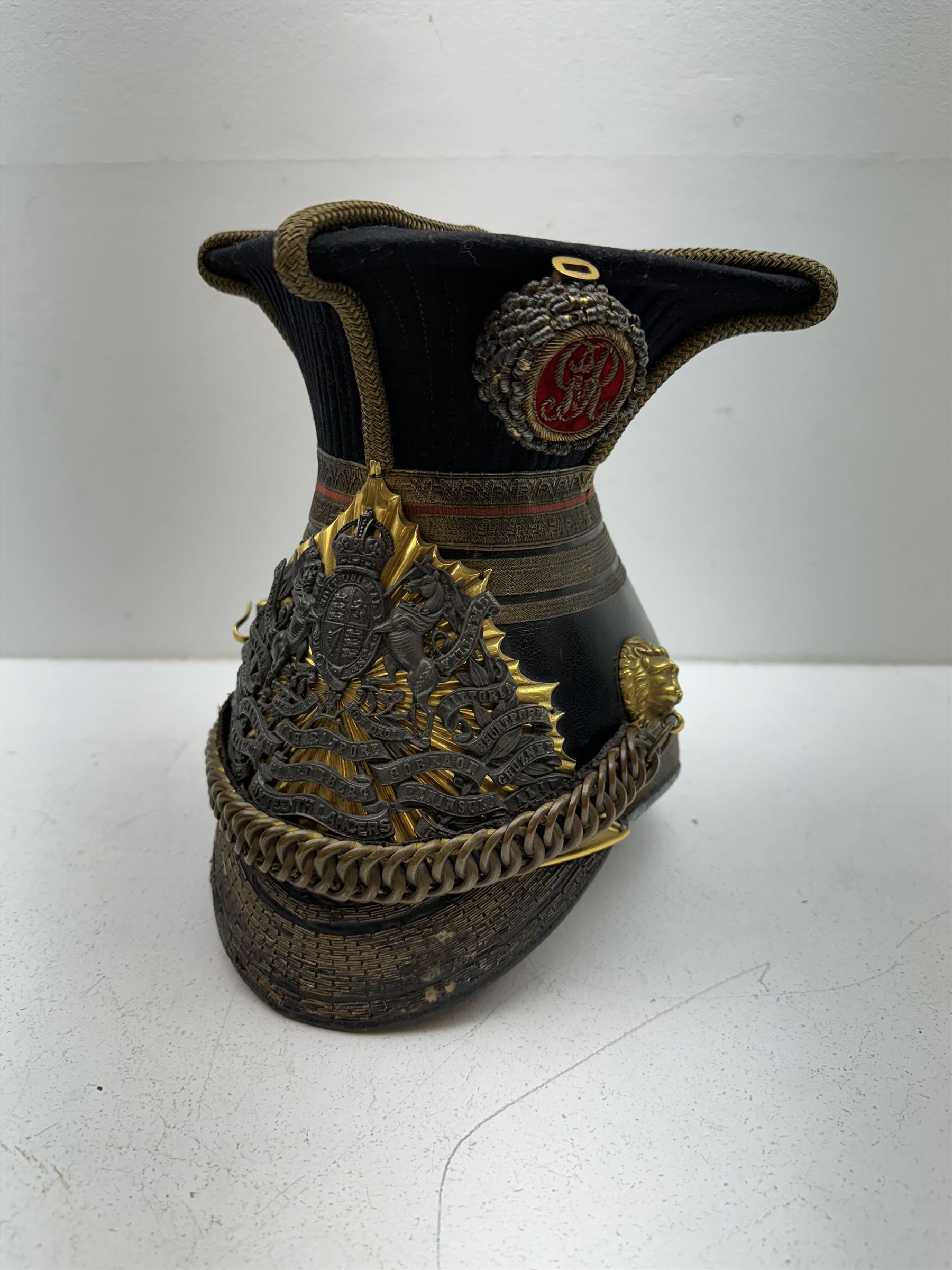 16th Queens Lancers Officers Lance Cap, black leather body with gilt braid lace and gilt wire braiding to the peak, officers silver gilt helmet plate to the front, the black cloth mortar board top with thick bullion wire, the bullion socket holder with embroidered GR cipher to the centre, lion head side bosses with velvet backed linked chinstrap, interior with leather sweatband and cloth lining, marked Carter & Co Pall Mall, the helmet is housed in japanned storage tin with brass plaque engraved “Lieu H L Evans, 16th Lancers'