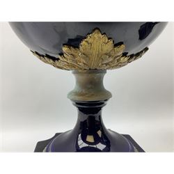 Pair of French large cobalt blue lidded urns, probably 19th century, the body decorated with ormolu ram's heads and ornate foliate design, the domed cover with brass berry finial, raised upon pedestal base with beaded decoration upon shaped plinth, H52cm