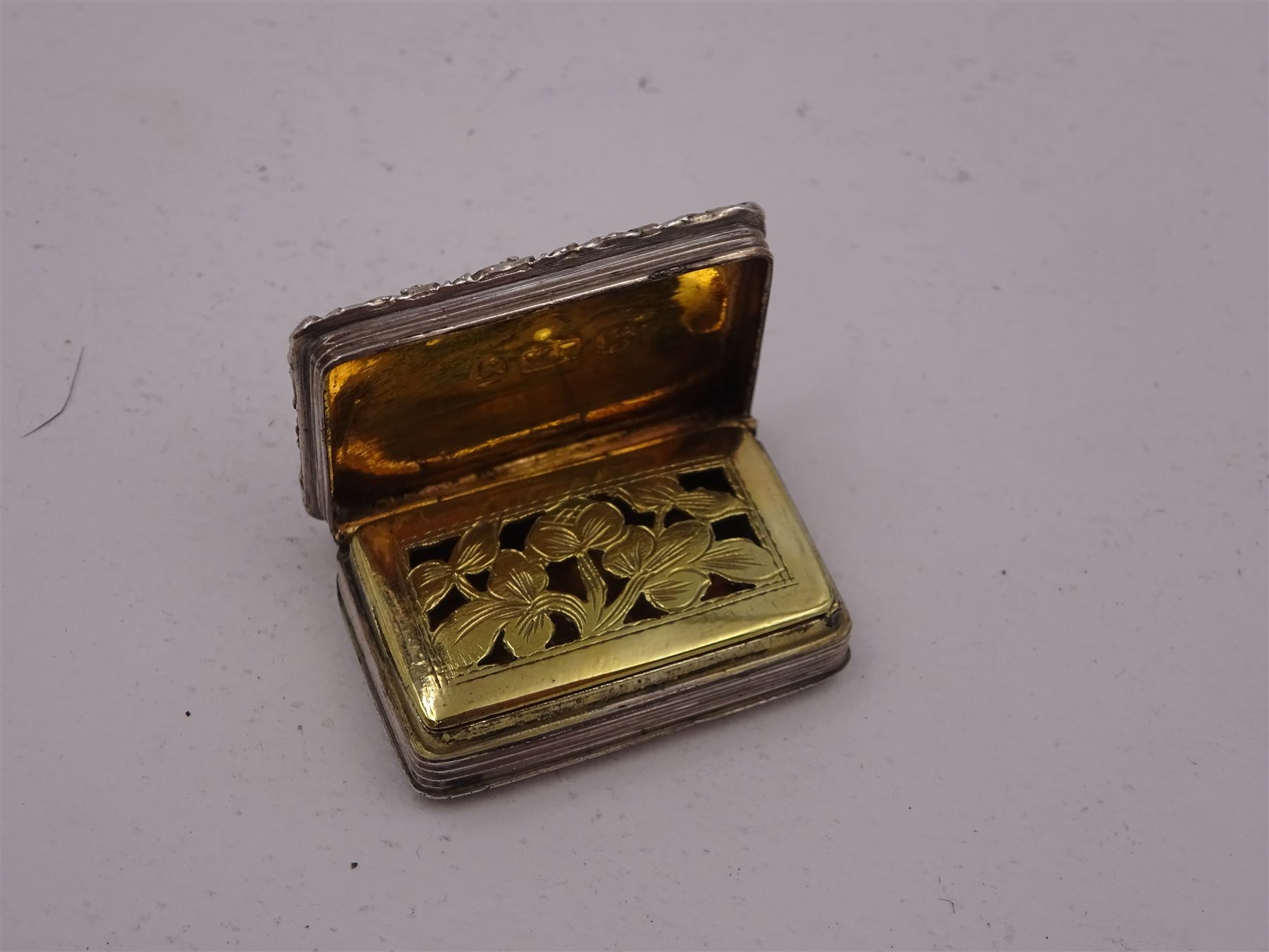 George III silver vinaigrette, of typical rectangular form, with raised foliate rim and engine turned decoration, with banded sides and foliate pierced engraving to gilt interior, hallmarked Birmingham 1797, maker's mark TS, L3cm