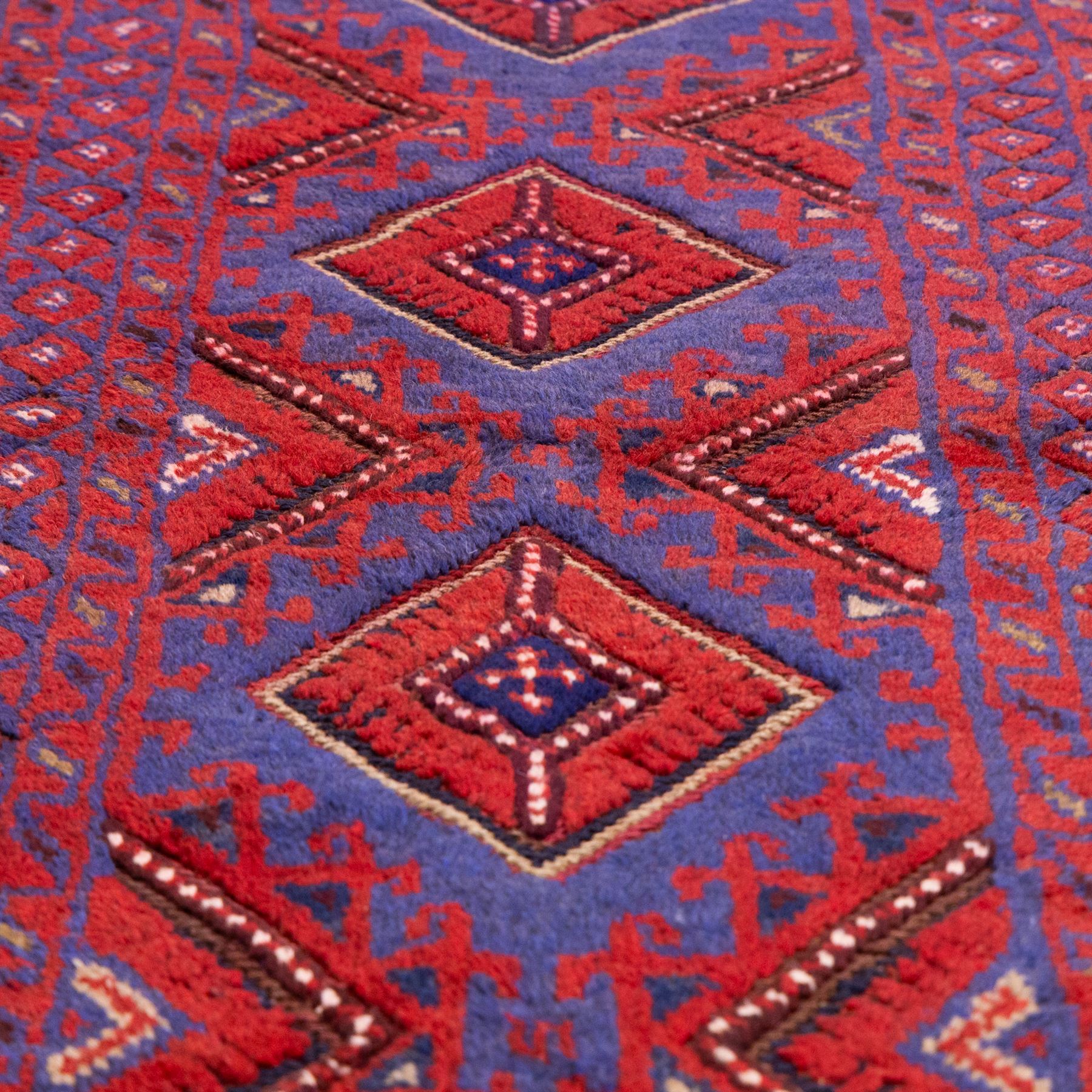 Afghan Meshwani runner, hand-knotted wool pile, indigo ground decorated with a vertical series of angular diamond medallions in tones of madder red, dark blue, framed by geometric borders with flatwoven kilim ends with fringe 