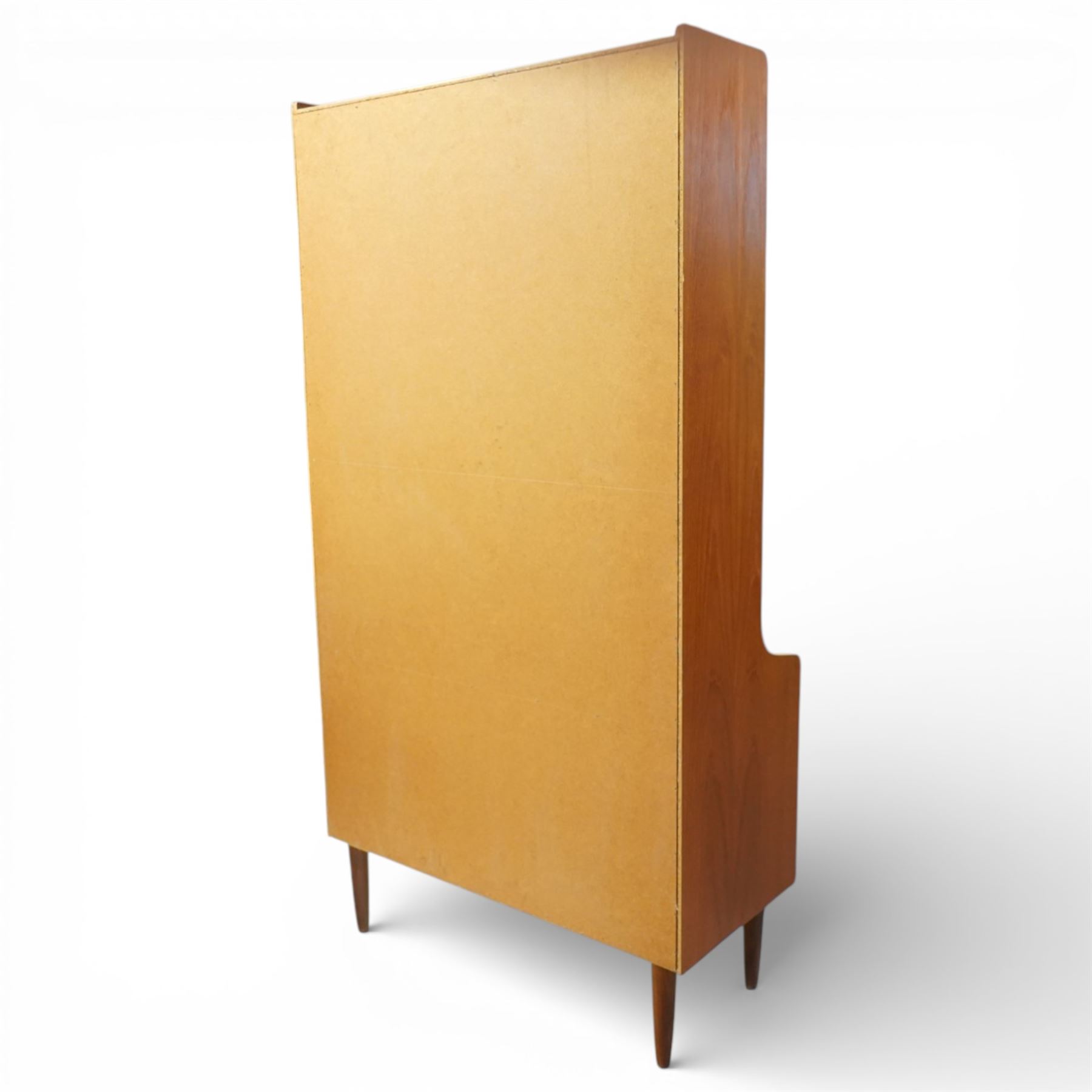 Mid 20th century Scandinavian teak bookcase cabinet in the manner of Johannes Sorth, the upper section with three open shelves over a shaped fall to a lower cupboard enclosed by sliding doors with recessed circular handles, raised on tapering supports