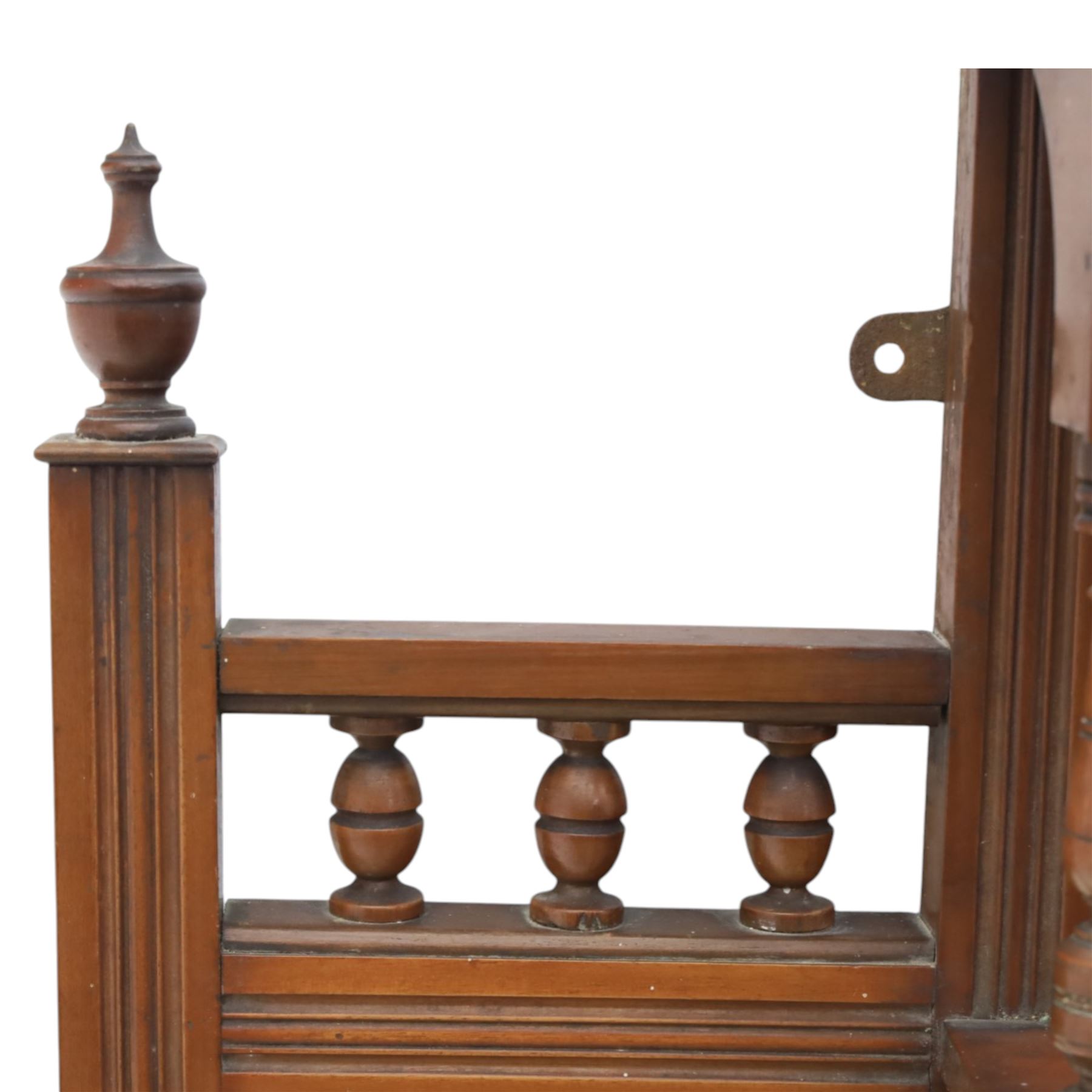 Edwardian walnut overmantel mirror, moulded cornice over three arched apertures with turned supports, flanked by open shelves with turned uprights and finials, carved foliate panels to the base