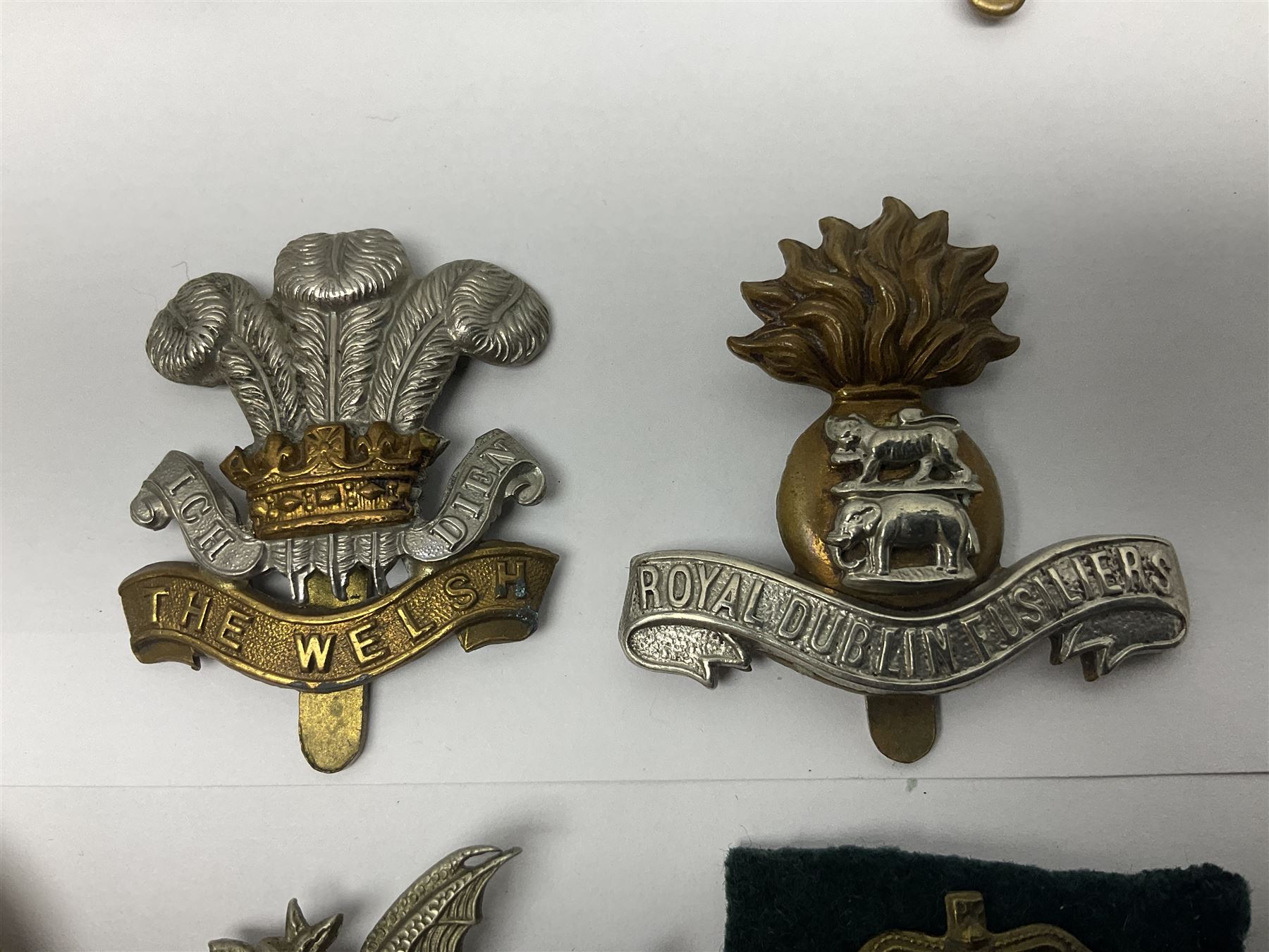 Fourteen cap badges of Irish interest including Royal Dublin Fusiliers inscribed to the slider 'From A. O'Connor 2nd Batt. Dec.2nd 1915', Connaught Rangers, South irish Horse Yeomanry, Inniskilling Fusiliers, Royal Irish Regiment etc; and seven Welsh badges including South Wales Borderers, Welsh Guards, 3rd Bn. Monmouthshire Regt. etc (21)