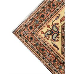 Persian ivory and peach ground, overall geometric design, the field with central star medallion surround stylised leaf motifs, guarded geometric design border