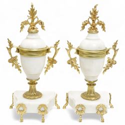 French-Early 20th century 8-day white marble and gilt metal striking portico mantle clock and garniture, Parisian drum movement with a white enamel dial, Arabic numerals and garland swags, two train countwheel striking movement sounding the hours and half hours on a bell. With a matching pair of conforming urns with gilt mounts. 