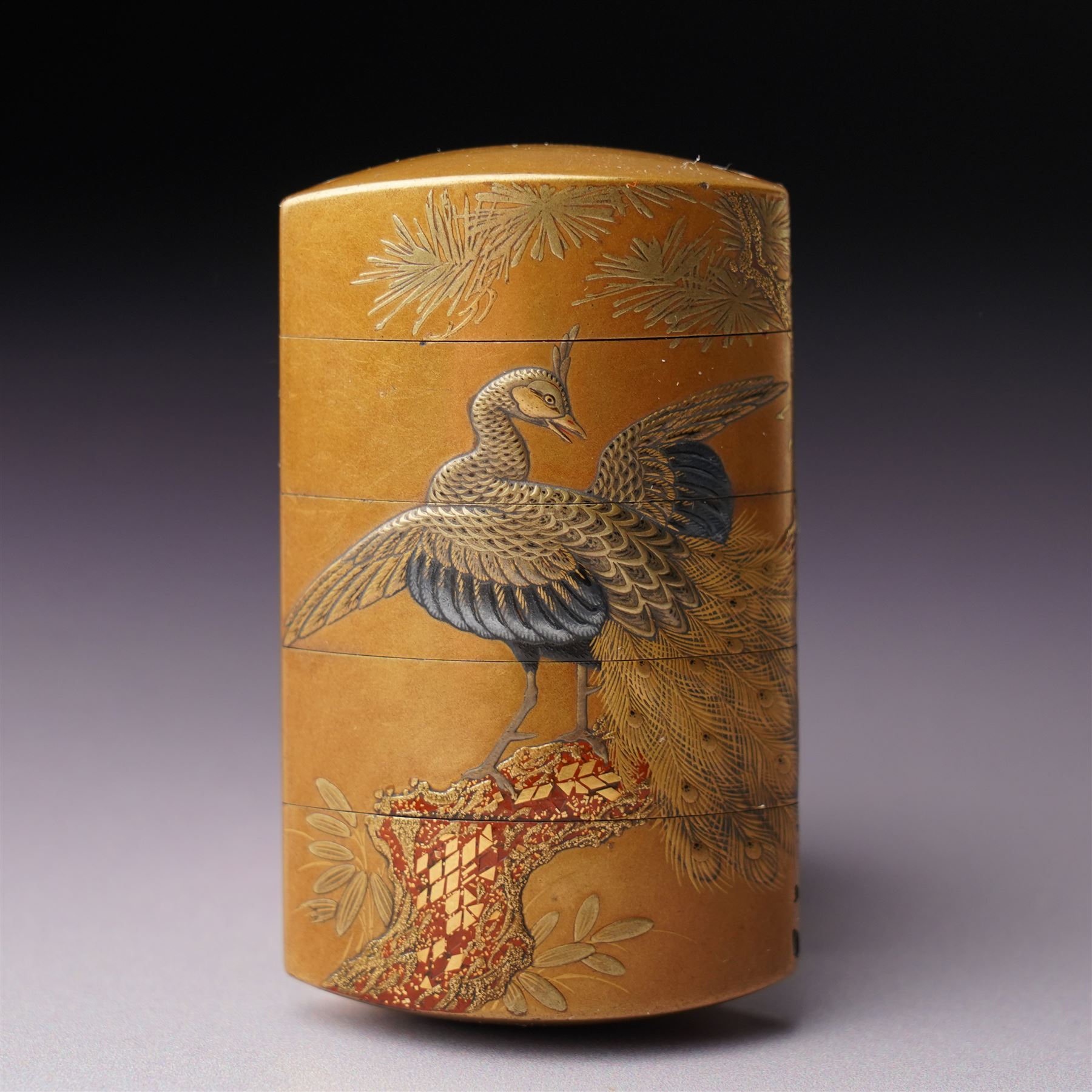 Minsetsusai Kyūho - Fine Japanese Meiji period gold lacquered four-case inro, of rounded rectangular form, the body with maki-e decoration depicting a peacock on a branch, the internal body with nashiji lacquer, artist's two character signature and kakihan to base, H6.5cm
Notes: For the artist, see see E. A. Wrangham, The Index of Inro Artists, Harehope, Northumberland, 1995, p. 158.
An inro would be an essential element of a gentleman's kimono, which typically lacked pockets. The stacked compartments could be used to hold medicine, which was particularly useful for Samurai warriors going into battle. 