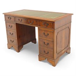 Late 20th century yew wood nine drawer writing desk, rectangular top inset with gilt-tooled green leather, above an arrangement of nine drawers with brass swan-neck handles, raised on bracket feet