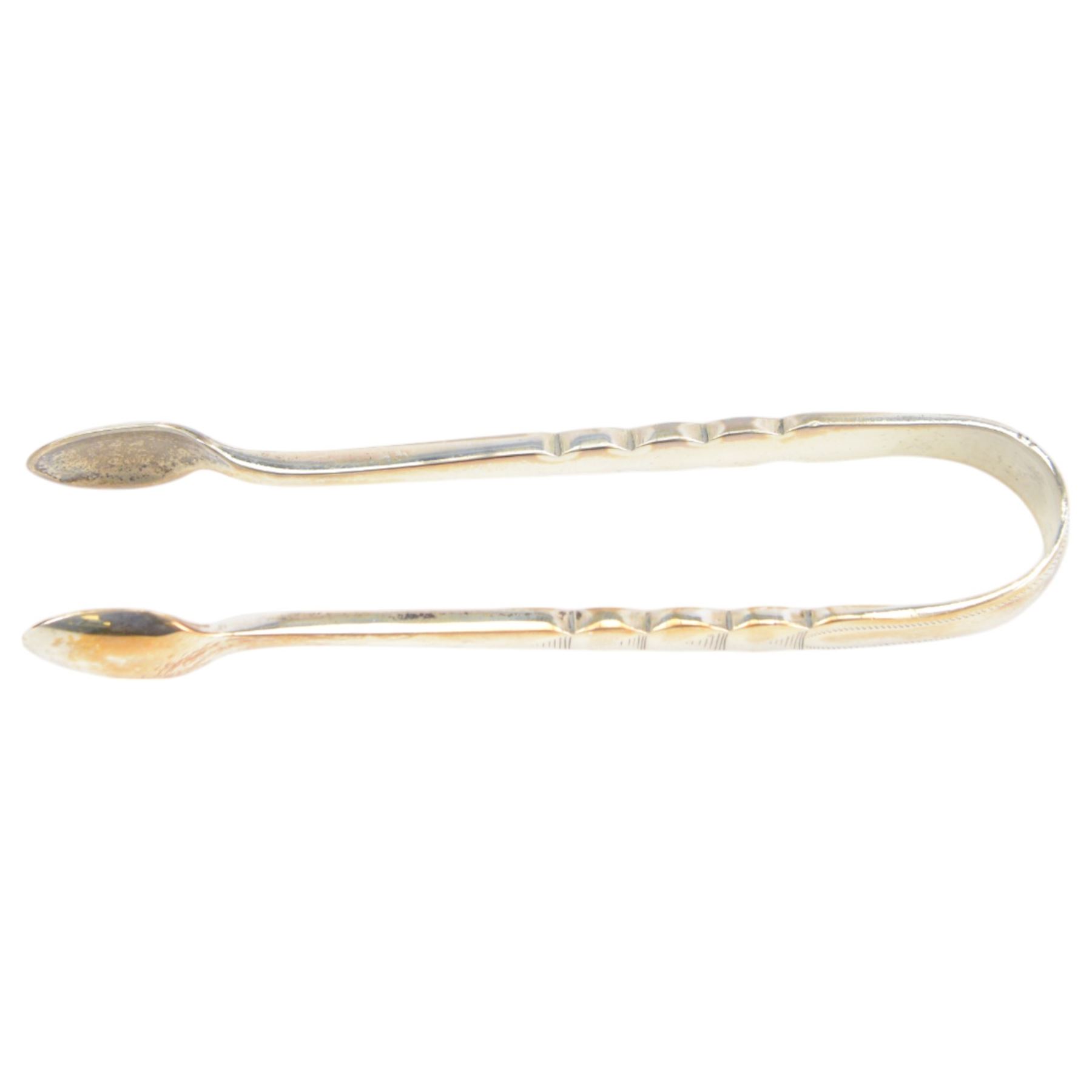 Edwardian silver shell butter dish, upon three bun feet, together with a matching shell spoon engraved with initial, both hallmarked Josiah Williams & Co, London 1906 and 1914, together with an Edwardian milk jug, open sucrier and sugar tongs, the jug and bowl of circular part fluted form with bead rim, hallmarked Mappin & Webb Ltd, Sheffield 1902, both sets contained within fitted tooled leather boxes with silk and velvet lined interiors