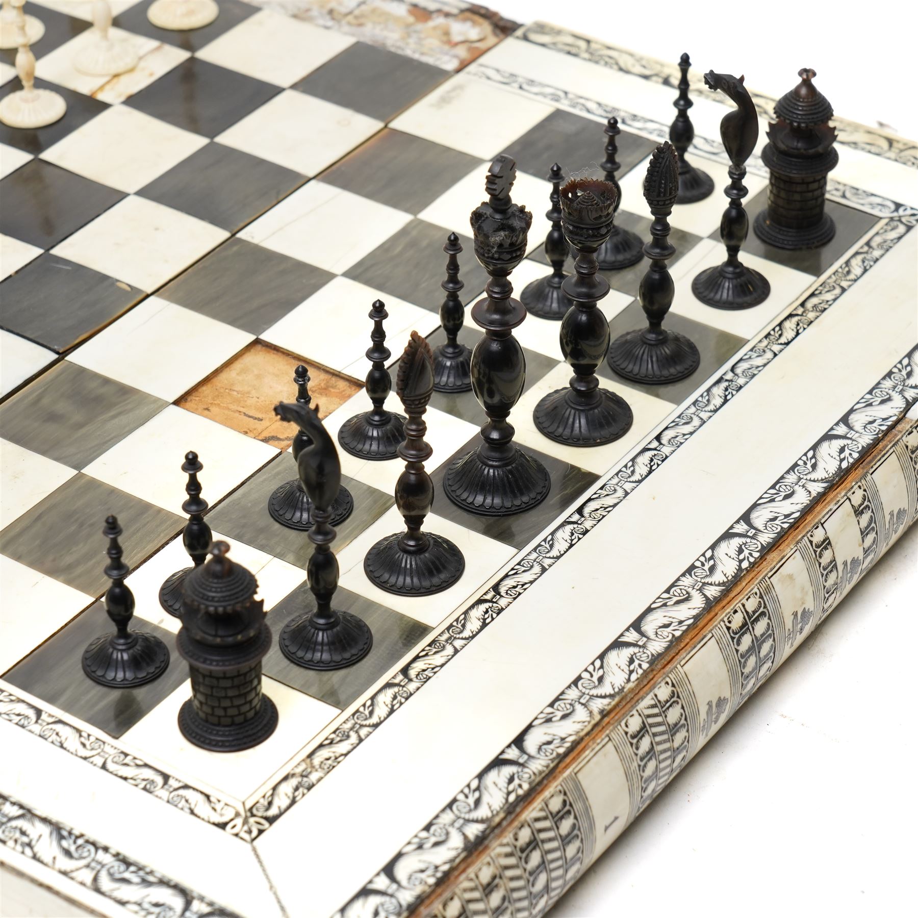 Mid-19th-century Anglo Indian Vizagapatam ivory, sandlewood, and horn veneered backgammon/chess board, circa 1860, rectangular games box the borders engraved with a stylized scrolling leaf decoration and spine engraved History of Persia the interior inlaid for backgammon, with three internal sandalwood boxes with covers, containing 16 ivory pieces and 16 horn pieces, comprising, kings and queens with pierced crowns on baluster carved shafts; bishops with carved mitres; knights represented by horses’ heads; and rooks as towers with imbricated decoration.

This item has been registered for sale under section 10 of the APHA Ivory Act, submission reference G68PNYA5 

