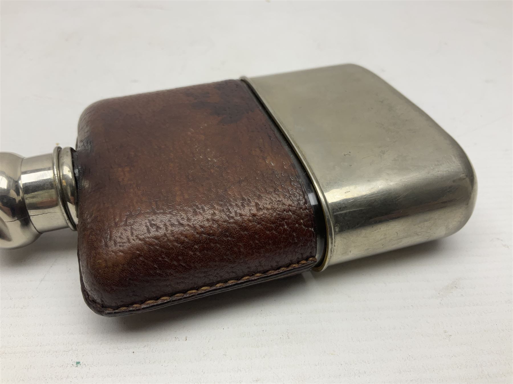 Silver plated glass and pressed leather hip flask, with swivel cap and removable cup, together with a similar oval example, engraved with wreath and initial B, tallest H16.5cm