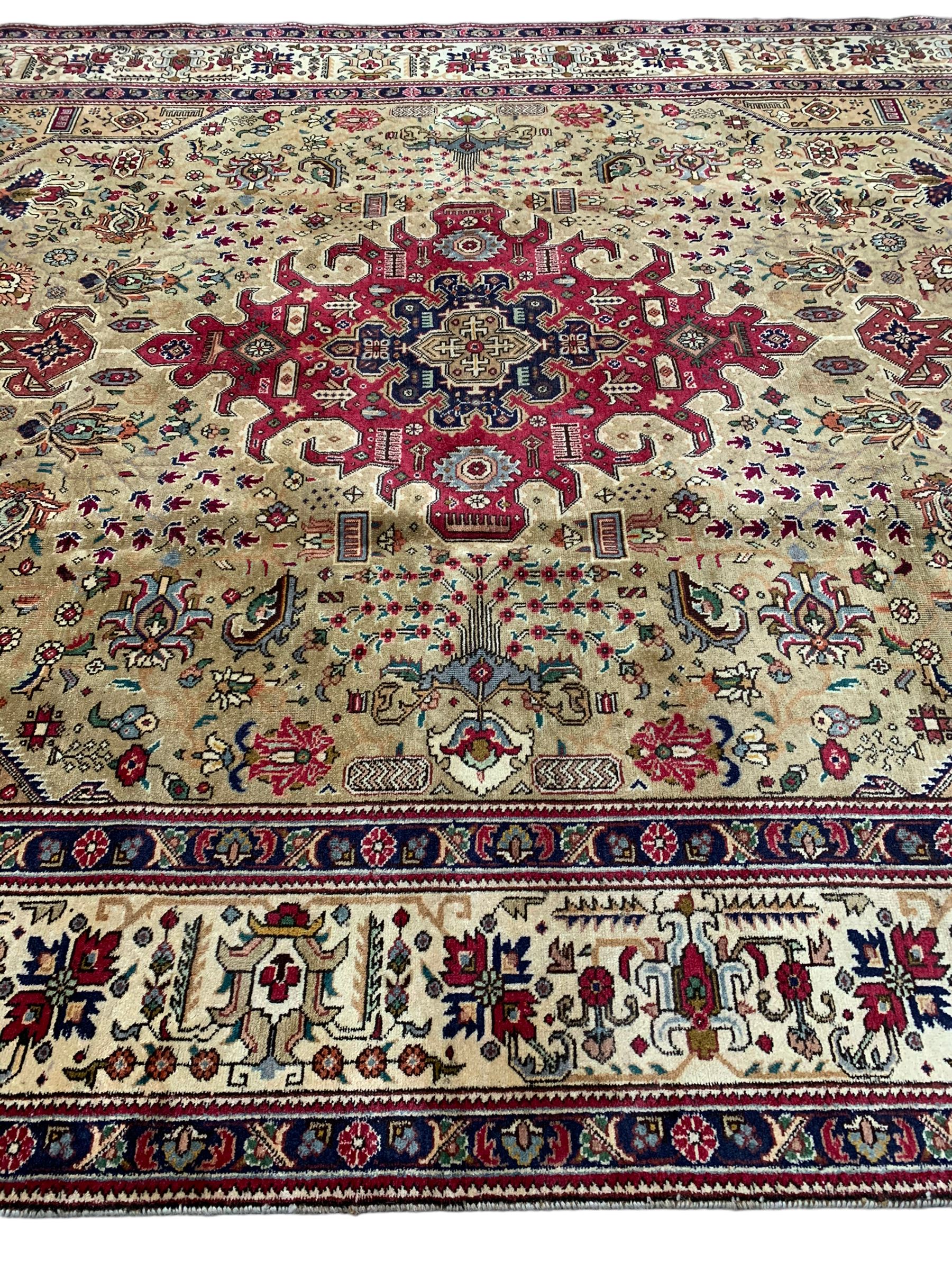 Persian Azarbaijan golden ground carpet, the shaped crimson ground medallion decorated with geometric motifs, the field profusely decorated with stylised plant and flower head motifs, repeating border with guard bands 