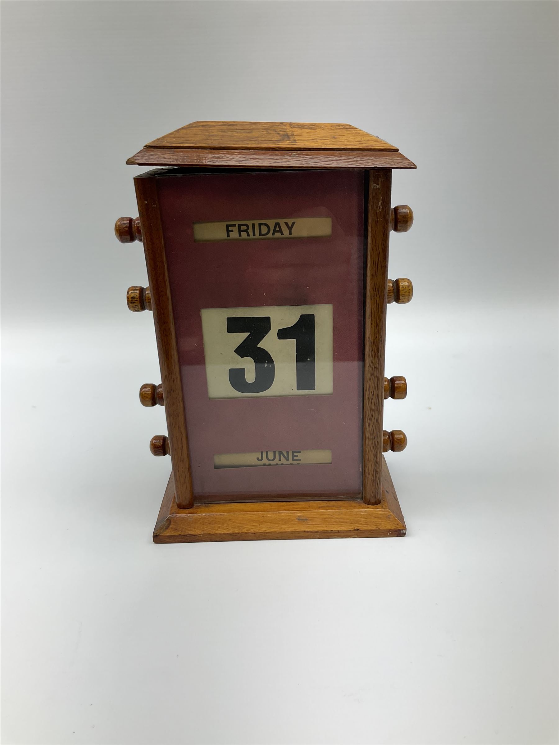 An early 20th century oak perpetual desk calendar, with three glazed apertures for day, date and month, H20cm