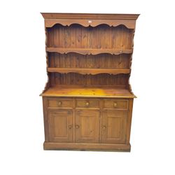 Pine dresser, raised back with projecting cornice and shaped apron over two tier plate rack, base fitted with three drawers and three panelled cupboard doors, on plinth base