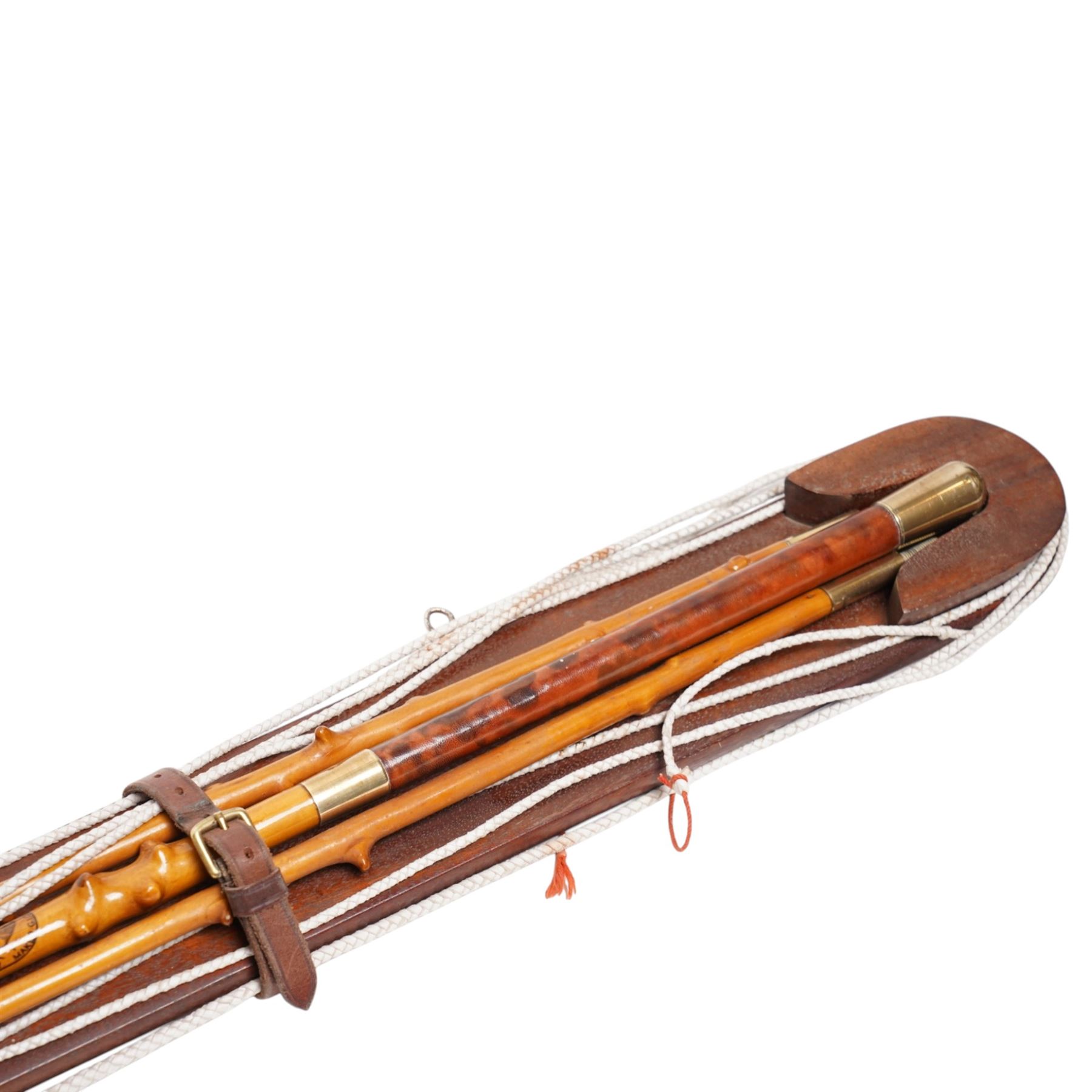 A Woodcock Hill - 20th century travelling coaching whip, the two part yew wood twisted shaft, with leather grip and brass collar and butt cap, with makers mark below the leather handle 'A Woodcock Hill Whip Maker G.I Clothier', together with an additional thong end, mounted upon a wall mounted holder, whip 142cm 