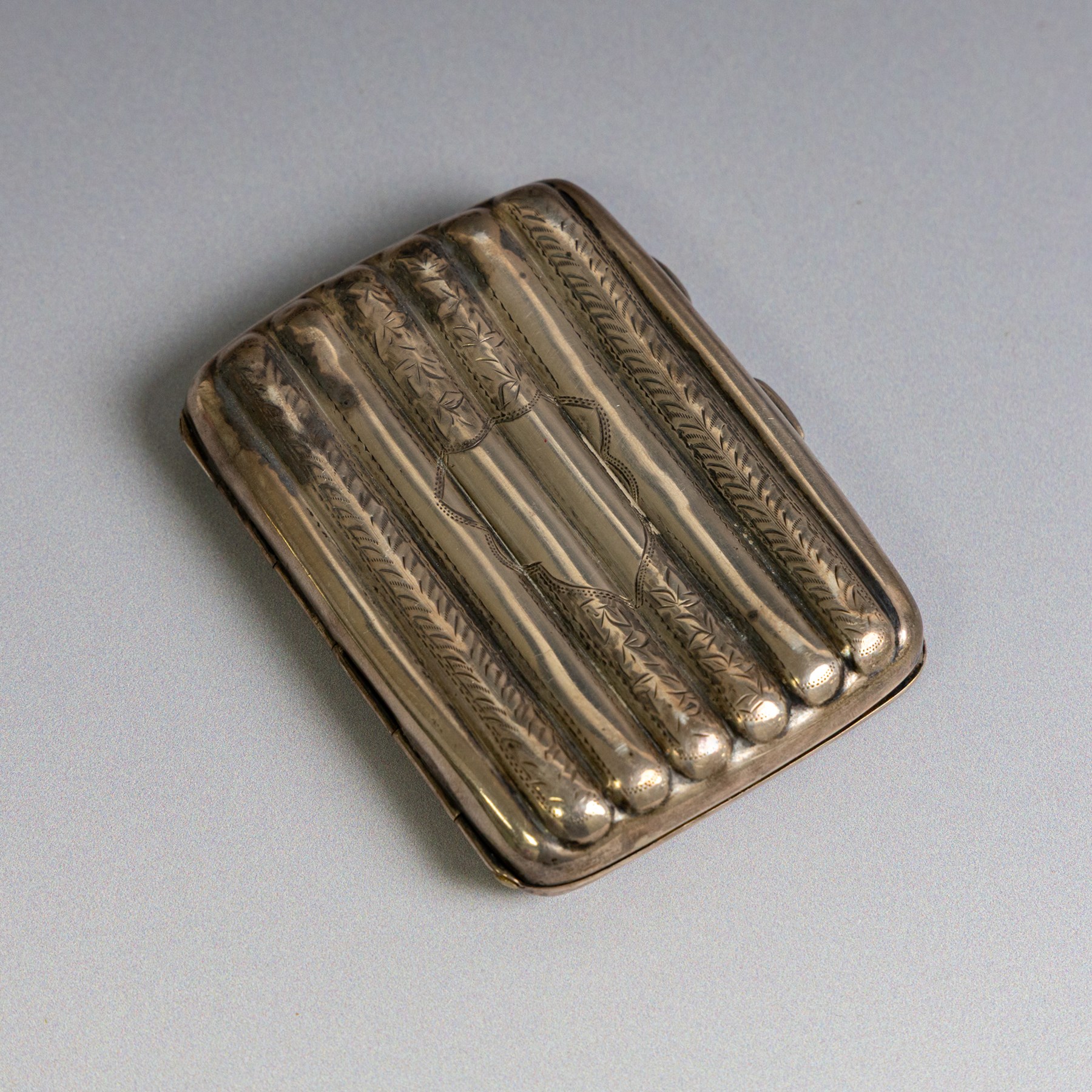 Two early 20th century silver cigarette cases, comprising a rectangular example with foliate decoration and vacant shield cartouche and a 1920s example with engine turned decoration and engraved initials, both hallmarked