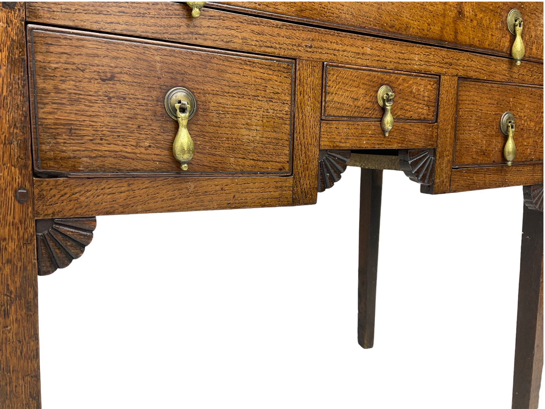 18th century Welsh oak lowboy, fitted with long drawer above three small drawers, square tapering supports, with fan carved corner brackets, circular plate and drop handles 