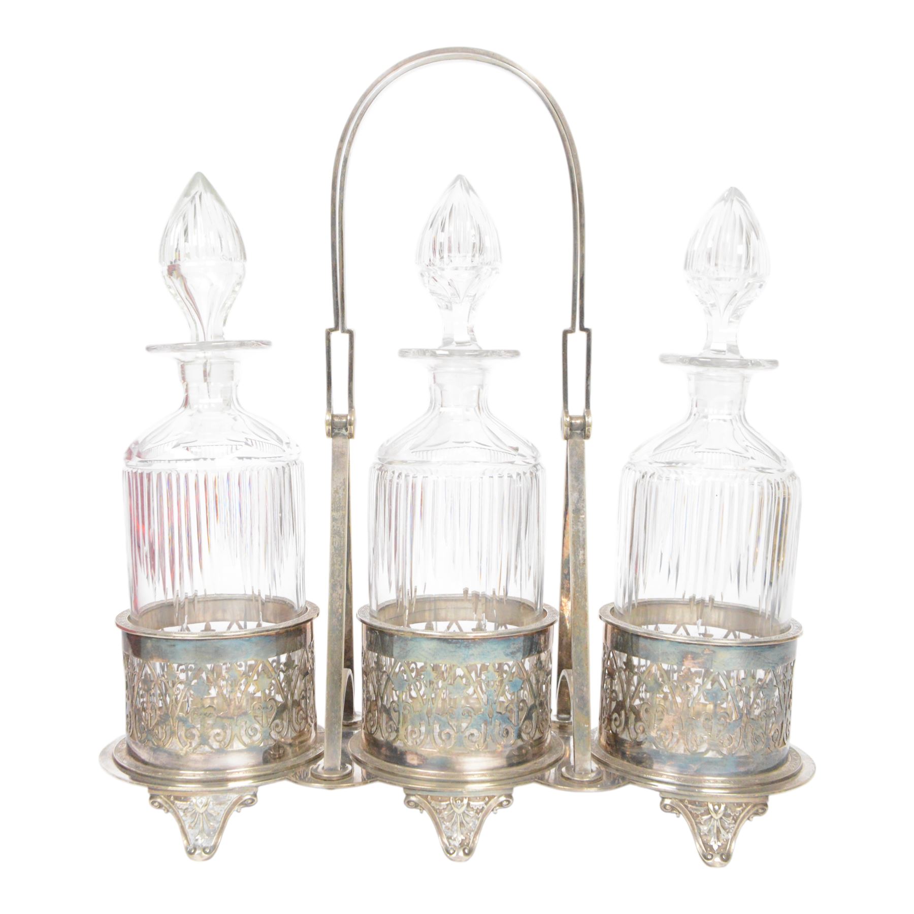 Late 19th century silver plated Silber & Fleming triple decanter stand, the three cut glass decanters with spire stoppers housed within foliate and scroll pierced bottle sleeves, upon a tripart base with six scroll feet, the base mounted with articulated x-frame curved handle, including handle when positioned upright H35.5cm, W34cm