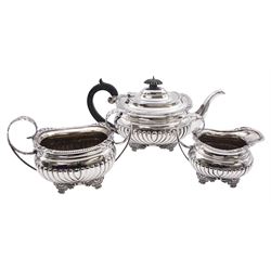 Early 20th century silver three piece tea service, comprising teapot, twin handled sucrier, and milk jug, each of oval part fluted form, with gadrooned and foliate cast rims, the teapot with ebonised handle and finial, the sucrier and milk jug with foliate detailed curved handles, each upon four stylised paw feet, hallmarked Edward Barnard & Sons Ltd, London 1911 and 1912, approximate gross weight 41.06 ozt (1277 grams)