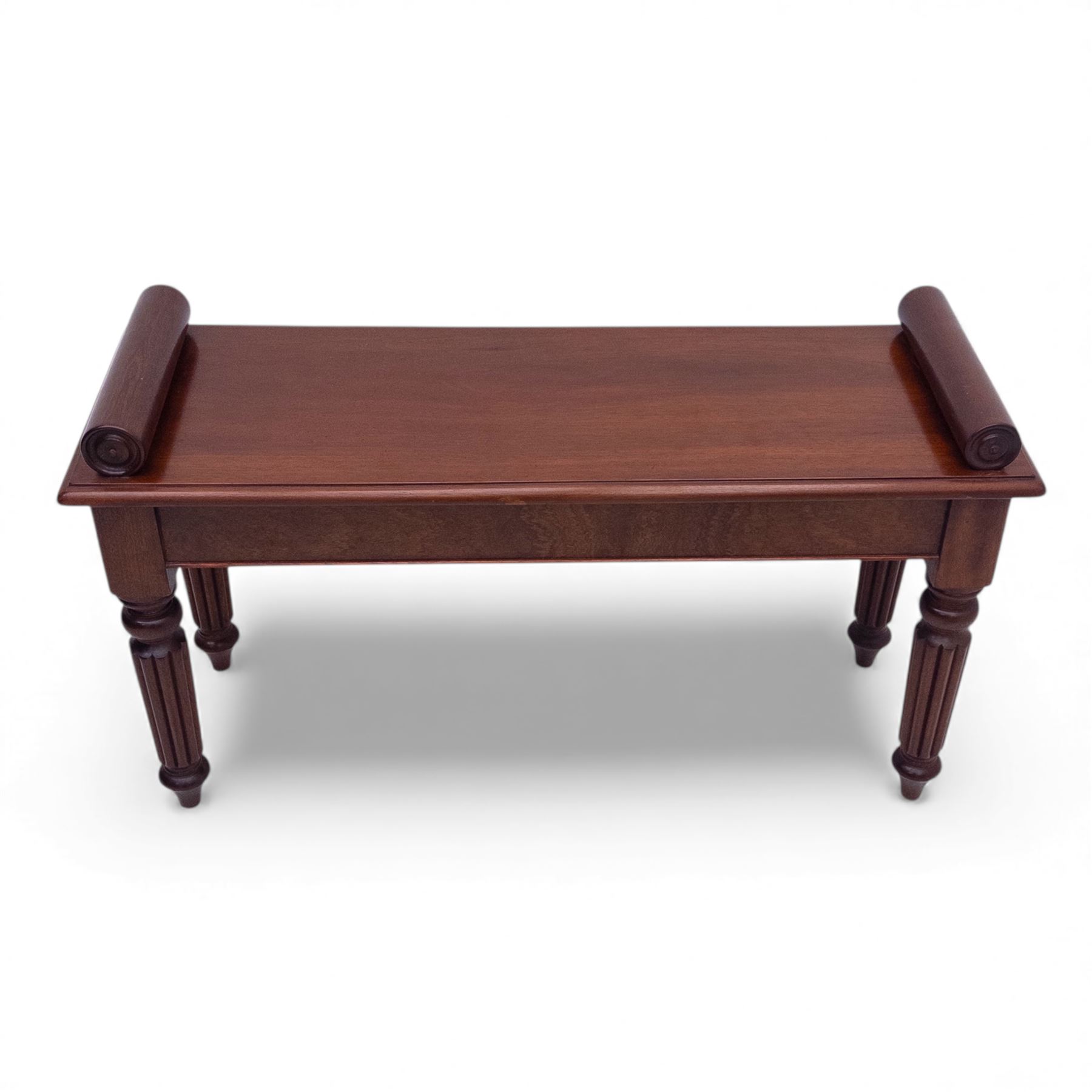 Regency style mahogany window seat, in the manner of George Bullock, with rectangular top with twin scroll ends, raised on four turned and reeded supports terminating in bun feet