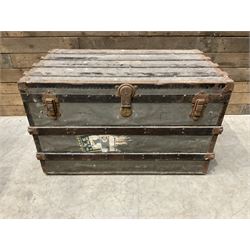Early 20th century wood and metal bound zinc travelling trunk, hinged top with three clasps, decorated with period luggage labels