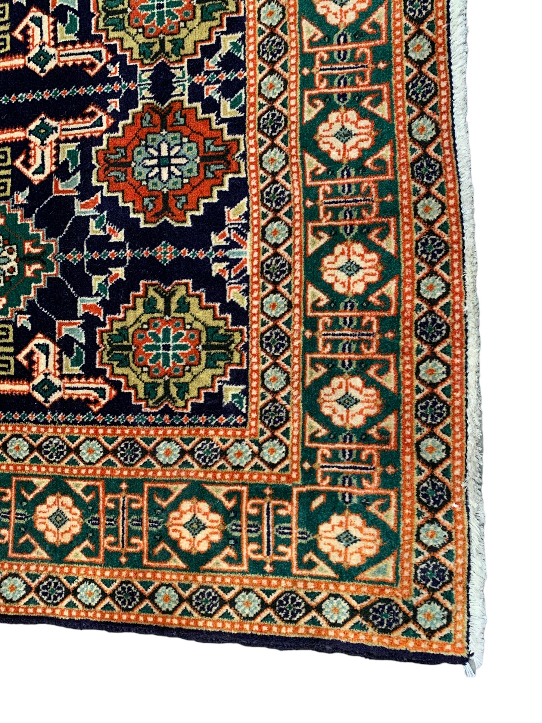 Small Persian indigo ground rug, the field decorated with Gilt motifs with trailing bead and stylised foliage, emerald green ground border decorated with geometric design and flower heads
