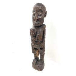 A large carved hardwood figure, African or Oceanic modelled as a mother and child with incised geometric decoration and inset shell eyes H119cm.